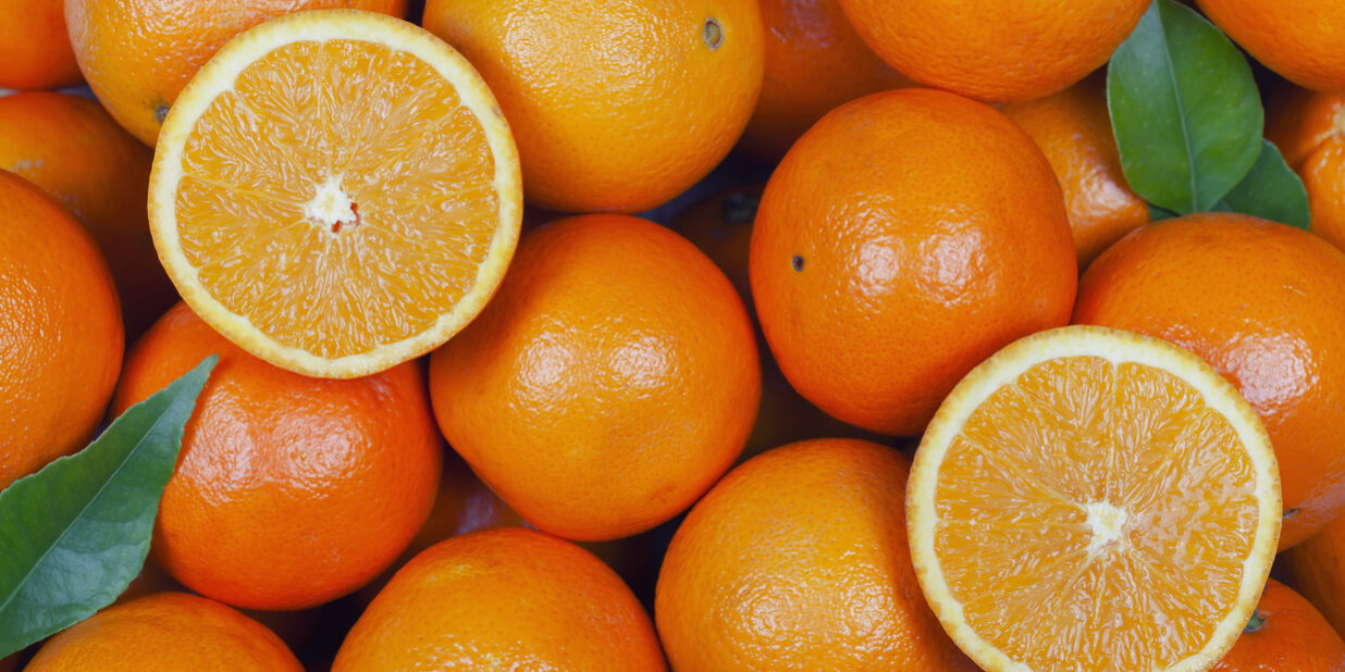 A lot of oranges with some cut in half and leaves